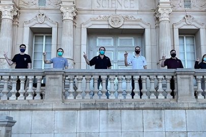 A row of students in Texas Tech University apparel in front of a mural of wind turbines.