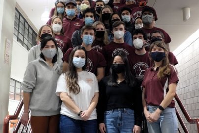 Students in masks standing on a staircase.