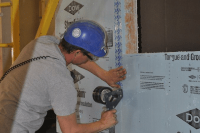 A man installing Styrofoam insulation inside a structure.