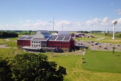 Red school with solar panels in front of a wind turbine.