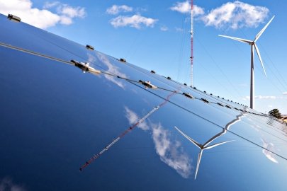 A wind turbine and solar panel on a sunny day.