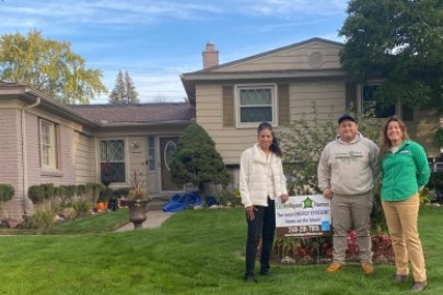 Three people standing in front of a house, facing the camera.