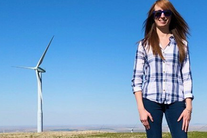 Lindsay Sheridan stands in a wind farm on a clear day.