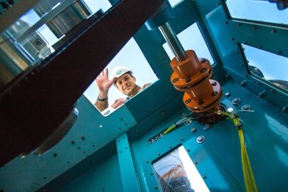 A person in a hard hart looks down a hatch past a turbine