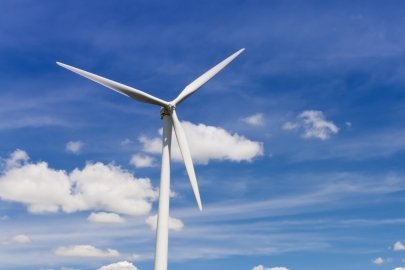 Wind turbine against a sunny sky with clouds.