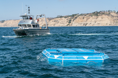 The hexagonal blue xWave floats near the ocean surface as a boat movespast. 