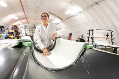 A researcher stands above a mold where a new material is being shaped into a turbine. 