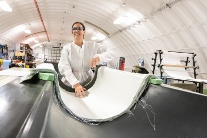 A researcher stands above a mold where a new material is being shaped into a turbine.
