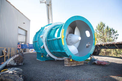 A large blue and white turbine is shown outside a warehouse building 
