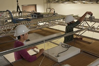 Two people working in a ceiling grid.