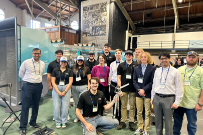 Team members of the Texas Tech collegiate wind competition stand around model wind turbines.