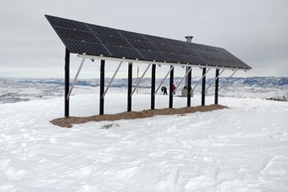 A solar array in the mountains surrounded by snow.