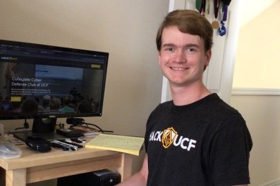 Photograph of Cameron Whitehead at a computer smiling