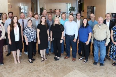Group of Leadership Development Program Graduates. About 20 people posing in a line in a sunny building lobby.