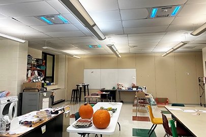 A high school classroom with hybrid UV-C air purifiers and whole-room disinfection luminaires with occupancy sensors that filter air during the day and disinfect surface and airborne pathogens at night.