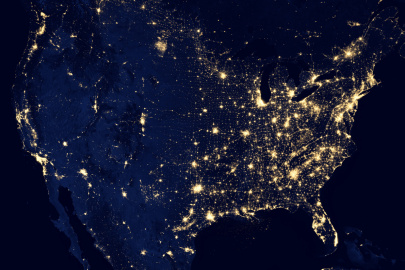 Satellite image of the United States at night with points of light emanating from the cities 