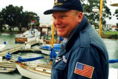 Man with a jacket that has an American flag patch on the sleeve and a hat