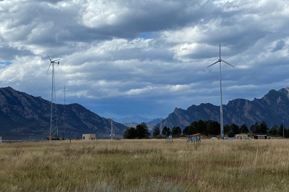 Multiple wind turbines in a filed outlined by mountains. 