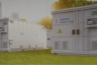 Battery storage containers with trees and windmills in the background.
