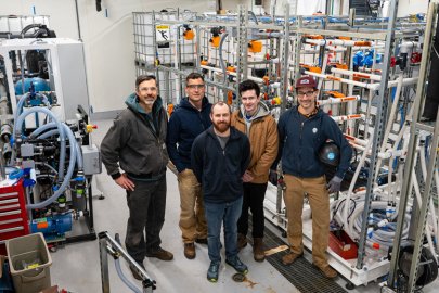 Several researchers standing among research equipment