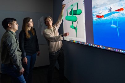 People stand in front of a large screen with models on it