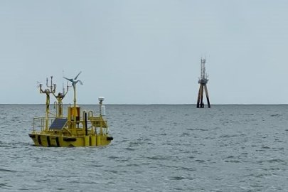 Buoy near wind turbine tower and ocean