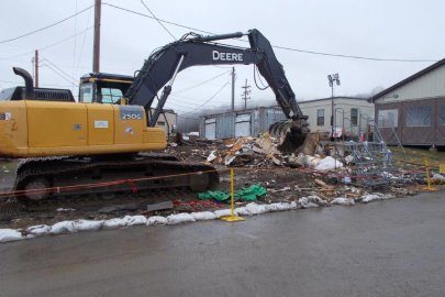A bulldozer demolishes an old guardhouse