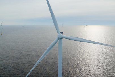 Close up of a wind turbine with water in background.