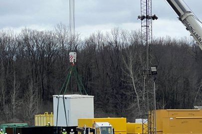 A crane loads large containers of waste onto a truck