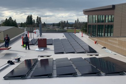 Two men install solar panels on a youth center roof.