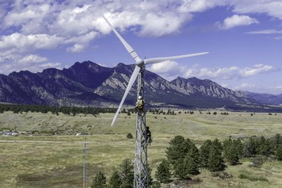 Two workers on a wind turbine with lattice tower construction.  