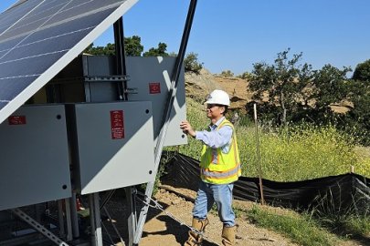 A person stands behind a solar skid panel.