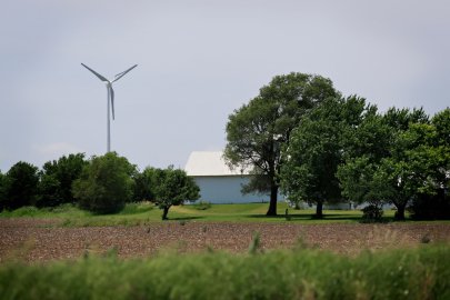 A small wind turbine next to a building in a rural setting.