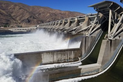 Side view of rapids coming ouf of a dam with mountains in the background