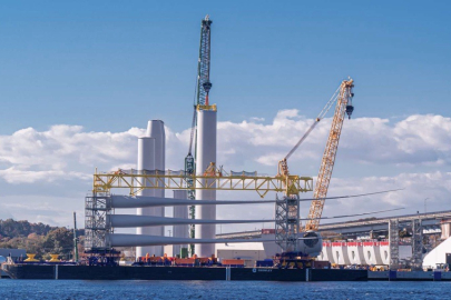 A barge carrying wind turbine blades and cranes at a port