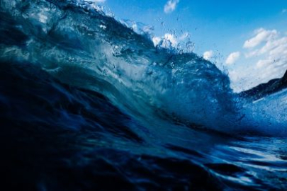 Picture of a wave crashing with blue sky in the background