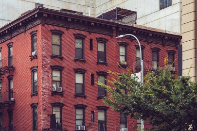 A multistory brick apartment building with a tree and streetlight.
