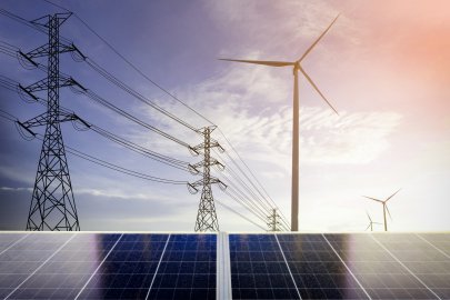 Powerlines, wind turbine, and solar panels with a clear sky behind them.