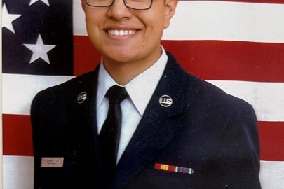 Man in uniform stands in front of American flag.