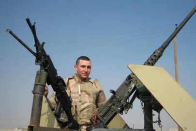 A man in a military uniform stands and poses for a picture between two large guns
