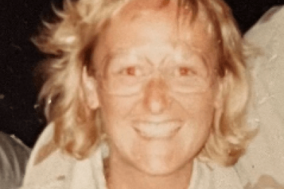 A woman with short, blonde hair and glasses smiles for a picture while wearing a military uniform