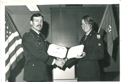Two people in military uniforms. One receiving an award. 