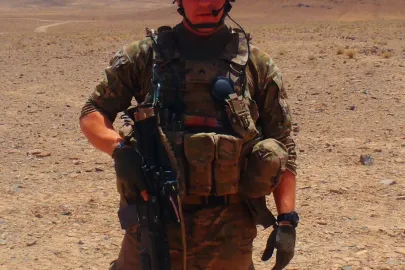 A military person in uniform in a desert.