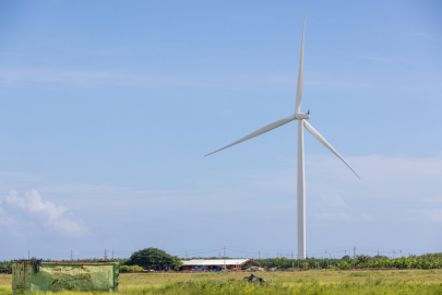 Wind Turbine on a farm next to a red building. 