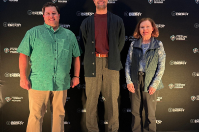 Three people stand against a backdrop of a wall of CyberForce branding.