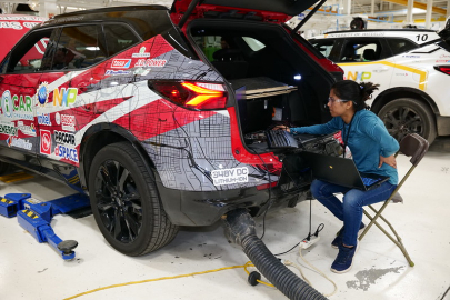 Woman working on a laptop connected to an electric vehicle