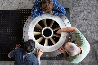 Three workers examining a hydropower turbine