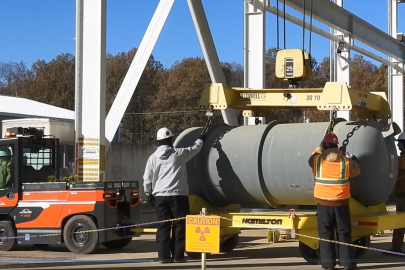 Employees using a tow motor to move a large cylinder