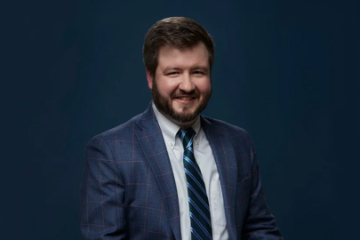 Matt Gurr posing for a portrait wearing a suit and tie.