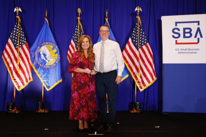 Photo of awardees of Lisa Tanner, Savannah River Nuclear Solutions (SRNS) small business liaison officer, and Dave Dietz, SRNS senior director of supply chain procurement, standing in front U.S. and Small Business Association lags.